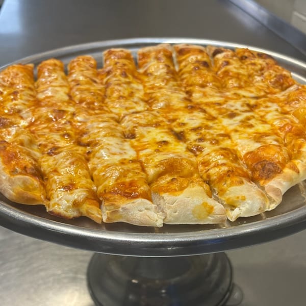 Cicero's Pizza cheese breadsticks, cut into strips, with melted cheese and sauce on a metal tray.