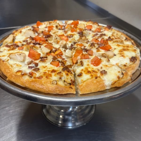 Cicero's Pizza with chicken, bacon, and diced tomatoes on a metal stand.