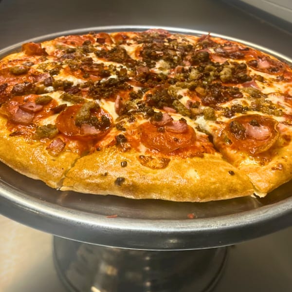 Cicero's Pizza with pepperoni, sausage, and ham on a metal pizza stand.